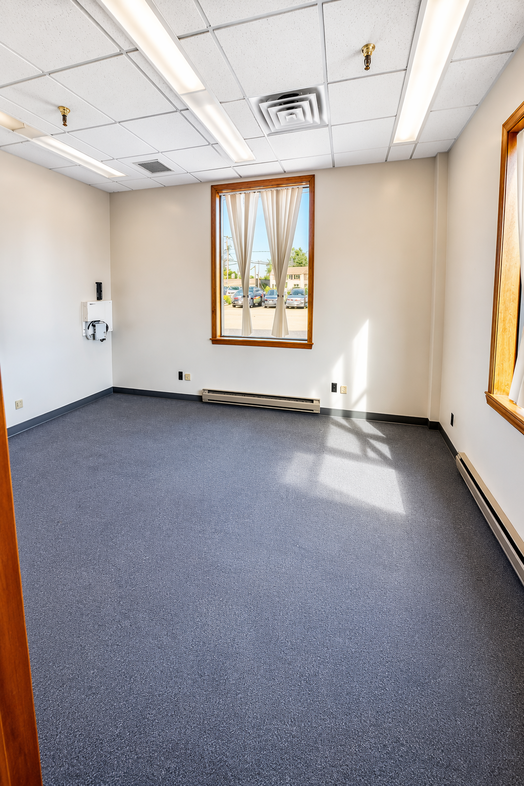 Interior photo of Suite 100. Yellow walls with a blue carpet and a window